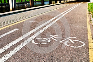 Bicycle white and yellow lanes sign and image of a bicycle with sun rays on road surface
