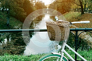 Bicycle wicker basket on the background of the river channel in the city