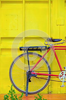 Bicycle on wood floor against container yellow wall