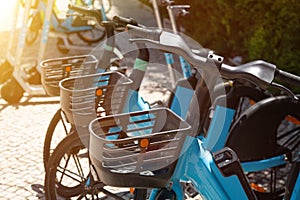 Bicycles with baskets are parked on the street of the city for rent.