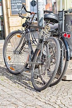 Bicycles lean against a lantern next to a trash can