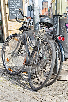Bicycles lean against a lantern next to a trash can