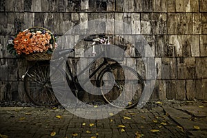 Bicycles old vintage flowers in a basket. Parked on the sidewall of the wooden house ideal for design work Classic vintage style photo