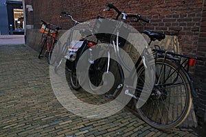 Bicycles parked against a red stone brick wall in an old alley