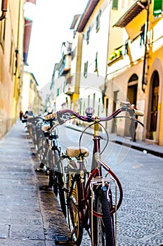 Bicycles parked on a pavement on a narrow street