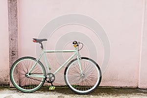 Bicycles parked by the pink color cement wall.