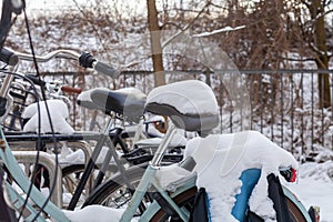 Bicycles with snow on the saddles, winter scene in Amsterdam, horizontal