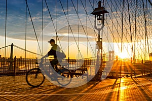 Bicyclist on Brooklyn Bridge during sunrise in New York. USA