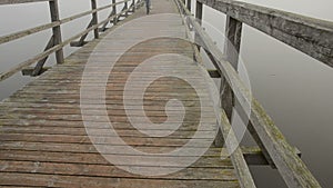 Bicyclists on wooden lake bridge and mist