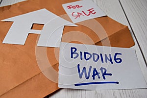 Bidding War and House For Sale write on sticky notes isolated on Office Desk