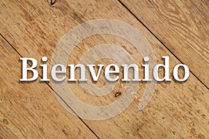 `Bienvenido` white text on a wooden background. Translation: `Welcome` photo