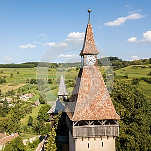 Biertan town and Biertan lutheran evangelical fortified church spires and clock tower. Transylvania, Romania. Aerial close view.