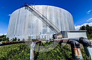 Abandoned Oil Refinery Gas Tank and Rusty Pipeline