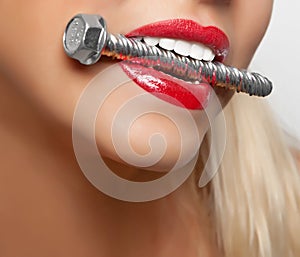 Big anchor bolt in the girl`s teeth with red lipstick painted lips.