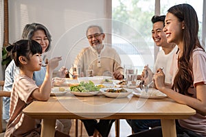 Big Asian happy family spend time having lunch on dinner table together. little kid daughter enjoy eating food with father, mother