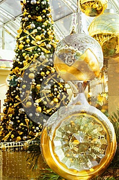 Big beautiful Christmas tree decorated with ornaments golden silver hanging balls bows garland sparkling lights in european city