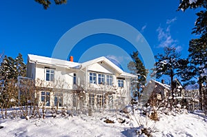 Big beige color wooden house in the countryside in winter. A typical traditional european village cottage with big panoramic windo