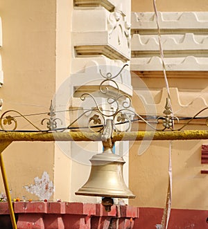 A big bell made with brass or copper hanging from a iron rod close up view.