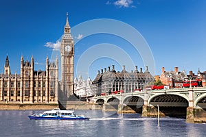 Big Ben with bridge over Thames and tourboat on the river in London, England, UK