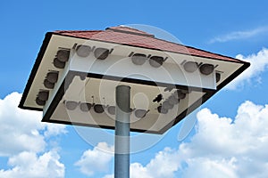 Big bird house with nest boxes under roof in front of blue sky