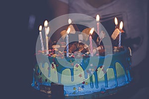 Big birthday cake with cream and candles for the birthday in the hands