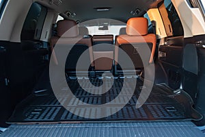 The big black empty trunk of SUV car with rubber mat and with leather folder on the floor Open luggage carrier of car closeup