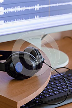 Big black headphones lie on the wooden desktop of the sound designer