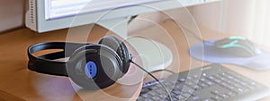 Big black headphones lie on the wooden desktop of the sound designer