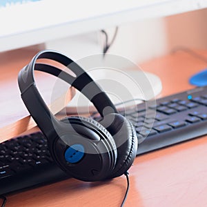 Big black headphones lie on the wooden desktop of the sound designer