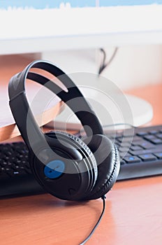 Big black headphones lie on the wooden desktop of the sound designer