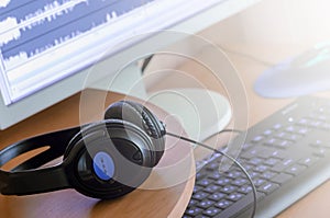 Big black headphones lie on the wooden desktop of the sound designer