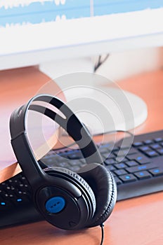 Big black headphones lie on the wooden desktop of the sound designer