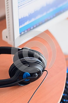 Big black headphones lie on the wooden desktop of the sound designer
