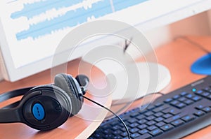 Big black headphones lie on the wooden desktop of the sound designer