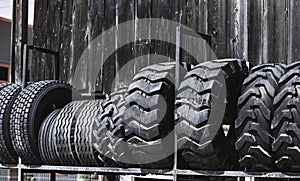 Big black huge big truck, tractor or bulldozer loader tires wheel close-up on stand, shop selling tyres for farming and big vehicl