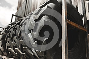 Big black huge big truck, tractor or bulldozer loader tires wheel close-up on stand, shop selling tyres for farming and big vehicl