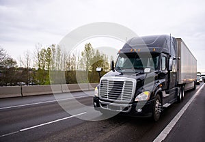 Big black modern semi truck rig trailer in traffic on highway