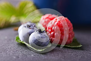 Big blue blueberries and raspberries on slate stone