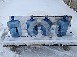 big blue and empty water bottles on benches in winter.