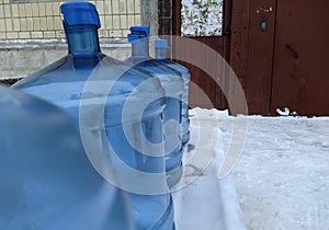 big blue and empty water bottles on benches in winter.