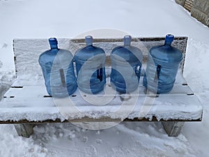 big blue and empty water bottles on benches in winter.