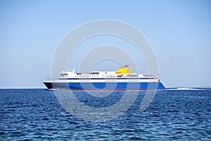 Big blue ferry boat floating on Aegean sea under a clear blue sky. Greece