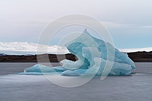 Big blue iceberg in front of a glacier