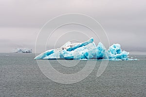 Big and blue icebergs floating around in the atlantic ocean near Greenland. Overcast sky.