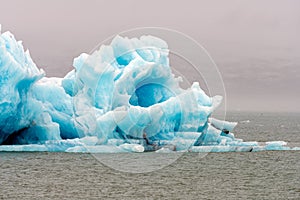 Big and blue icebergs floating around in the atlantic ocean near Greenland. Overcast sky.