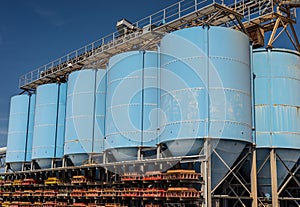 Big blue metallic Industrial silos for the production of cement at an industrial cement plant on the background of blue sky.