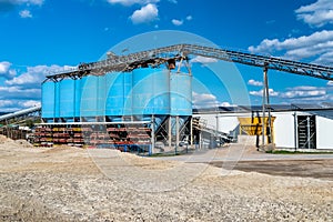 Big blue metallic Industrial silos for the production of cement at an industrial cement plant on the background of blue sky.