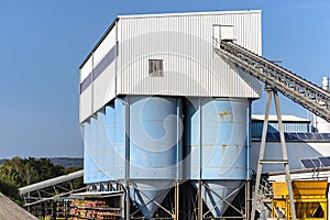 Big blue metallic Industrial silos for the production of cement at an industrial cement plant on the background of blue sky.