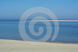 The big blue ocean with a blue sky and a long empty beach in the daylight