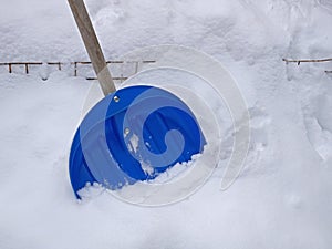 Big blue plastic shovel on fresh snow